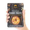 Hand holding a package of Siam Massaman Curry Paste with Tamarind & Lemongrass.