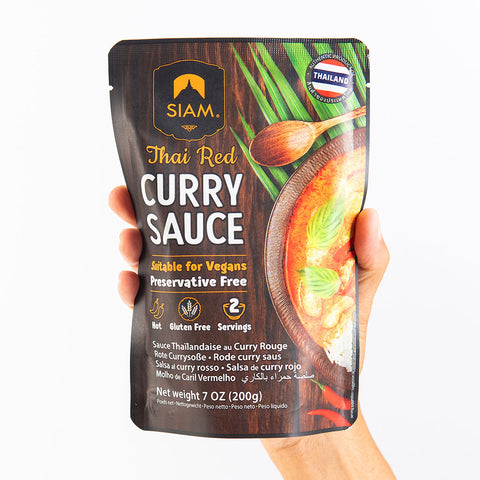 Packaged Thai Red Curry Sauce held by a hand on a white background