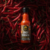 Bottle of Spicy Sriracha sauce surrounded by red chilies on a dark background