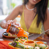 Person pouring sweet chili sauce over a salad
